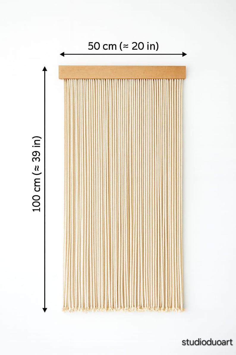 May include: Beige rope curtain, 39 inches long and 20 inches wide, with a wooden header. The curtain is made of numerous vertical ropes, creating a textured, natural look. The studio name is visible at the bottom.