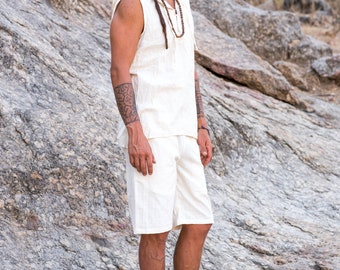 Könnte beinhalten: Cremefarbenes ärmelloses Hemd und Shorts-Set. Das Hemd hat eine Kapuze und die Shorts sind knielang. Das Outfit ist aus einem strukturierten Stoff gefertigt. Die Person steht auf einer felsigen Oberfläche.