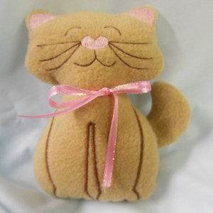 May include: A plush brown cat toy with embroidered facial features and a pink ribbon around its neck.
