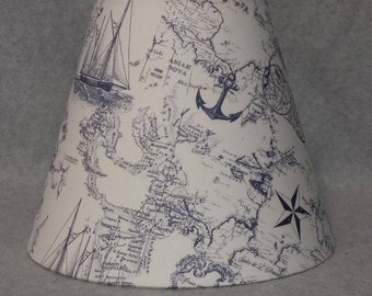 May include: A white lampshade with a nautical map print featuring an anchor, a compass, and a sailboat. The map is in black and blue ink on a white background.