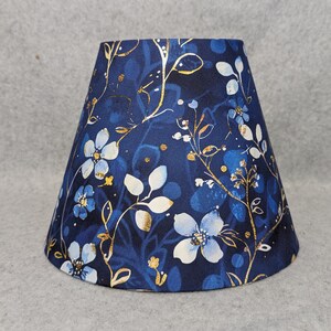 Lite blue flowers on blue lamp shade.  Shades of blue background.  Colorful.  Plants.  Flowers. Ninthisle. Shades are 9.5" x 5" x 7" tall
