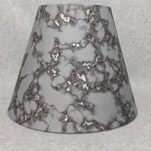 May include: A gray lampshade with a silver marble pattern.