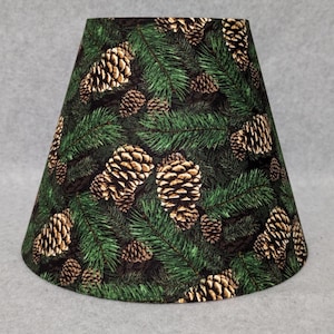 May include: A green lampshade with a pine cone and evergreen pattern.