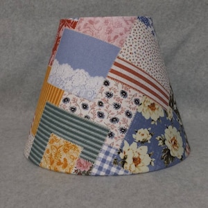 May include: A patchwork lampshade with a variety of floral and geometric patterns in shades of blue, yellow, red, and white.