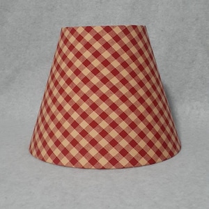May include: A red and cream gingham lampshade with a conical shape.