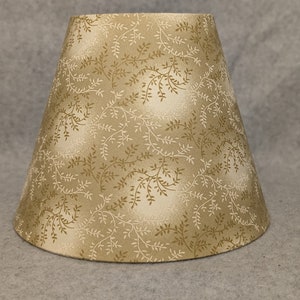 May include: A beige lampshade with a white floral pattern. The lampshade is made of fabric and has a conical shape.
