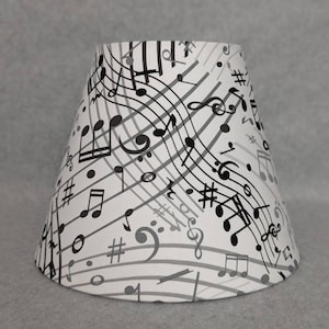 May include: A white lampshade with a black and gray musical note pattern.