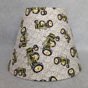 May include: A lampshade with a gray and white background featuring a repeating pattern of green tractors.
