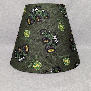 May include: Green lampshade with a repeating pattern of John Deere tractors and logos.