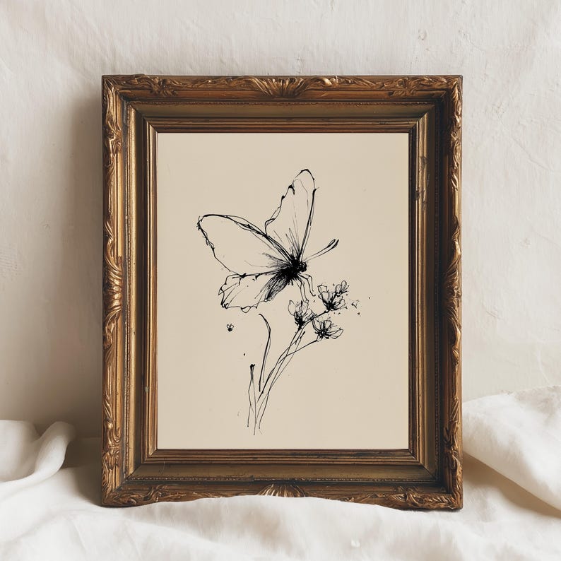 May include: A framed black and white ink drawing of a butterfly perched on a flower. The artwork is in a gold ornate frame. The background is a cream color.