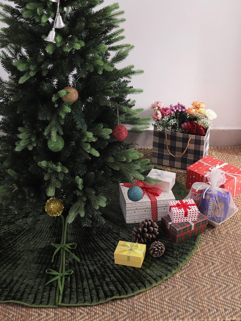 Puede incluir: Un &aacute;rbol de Navidad decorado con adornos y una falda de &aacute;rbol verde. Varios regalos envueltos en varios patrones y colores est&aacute;n dispuestos alrededor de la base del &aacute;rbol, junto con pi&ntilde;as y una caja de flores.