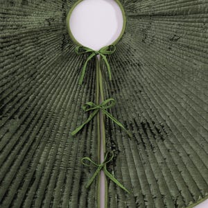 Puede incluir: Una falda de &aacute;rbol de Navidad de terciopelo verde con una abertura circular y un dise&ntilde;o plisado radiante. La falda tiene un ribete verde y se asegura con tres juegos de lazos de cinta verde. La falda est&aacute; dise&ntilde;ada para rodear la base de un &aacute;rbol de Navidad.