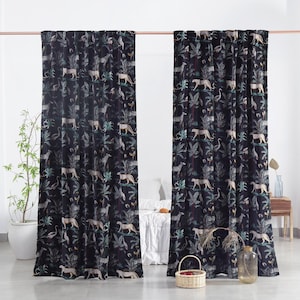 Puede incluir: Dos cortinas de terciopelo azul oscuro con un estampado de jungla. El diseño presenta leopardos, cebras, aves y exuberante follaje verde. Las cortinas cuelgan de una barra de color cobre, añadiendo un toque de elegancia.