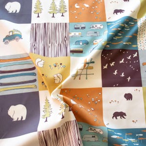 May include: A fabric featuring a grid pattern with various illustrations including white bears on dark blue, green pine trees, orange landscapes with birds, vintage campers, wood grain textures, squirrels, colorful canoes, and flying birds.