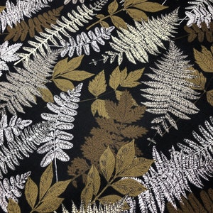 May include: A black fabric with a repeating pattern of stylized leaves and ferns in shades of white, gold, and brown. The design features various leaf shapes and textures, creating a natural, botanical theme.