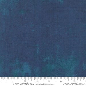 May include: A close-up of a dark blue fabric with a subtle mottled texture. The fabric is a solid color with a slight variation in shade. The fabric is measured in inches with the text "moda" printed on the ruler.