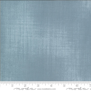 May include: A close-up of a piece of blue fabric with a textured, distressed appearance. The fabric has a subtle, mottled effect, with lighter areas creating a sense of depth. A ruler is at the bottom of the image.