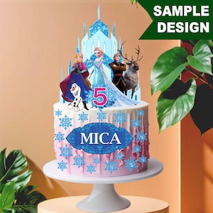 Könnte beinhalten: Ein rosa und weiß glasierter Kuchen mit blauen Schneeflocken-Dekorationen und einem blauen Banner mit der Aufschrift "MICA". Der Kuchen ist mit einem glitzernden blauen Schloss und Figuren aus dem Film Frozen gekrönt.