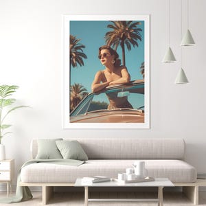 May include: A framed print depicts a woman in sunglasses leaning on a vintage car, with palm trees and a blue sky in the background. The artwork evokes a retro, sunny, and stylish aesthetic, perfect for adding a touch of vintage charm to any space.