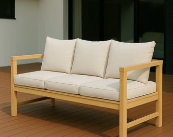 May include: A light-colored wooden outdoor sofa with three cream-colored cushions and a matching seat cushion. The sofa has a rectangular frame and armrests. The sofa is on a brown wooden deck.