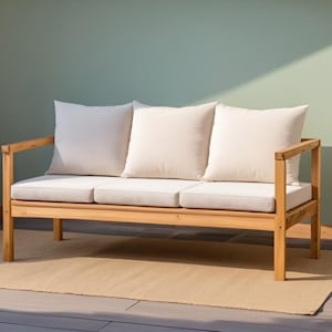 Op de afbeelding: Een houten buitenzitbank met drie crèmekleurige kussens en een lichtbeige zitting. De bank staat op een beige tapijt, met een lichtgroene muur op de achtergrond. De bank heeft een natuurlijke houten afwerking.