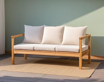 May include: A wooden outdoor sofa with three cream-colored cushions and a light beige seat. The sofa sits on a beige rug, with a light green wall in the background. The sofa has a natural wood finish.