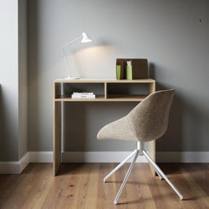 Puede incluir: Un escritorio moderno con acabado de madera clara, con una estantería incorporada y una lámpara de escritorio blanca. Una silla de tela beige con base plateada se encuentra frente al escritorio. La habitación tiene pisos de madera y paredes grises.