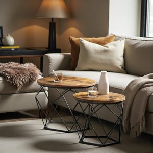 Puede incluir: Dos mesas auxiliares redondas con tapa de madera envejecida y base geométrica de metal negro. Una mesa tiene una botella blanca y un vaso de agua. Las mesas están en un salón.