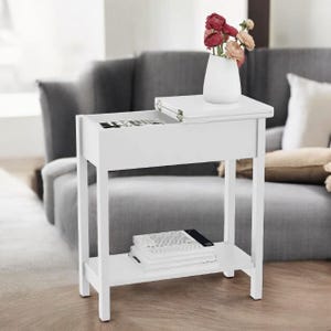 May include: A white side table with a top surface, a drawer, and a lower shelf. A white vase with pink and red flowers sits on top. The drawer is open, revealing items inside. A stack of books rests on the lower shelf.