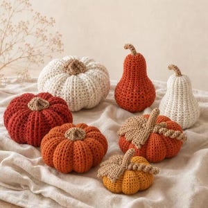 May include: A collection of seven handmade crochet pumpkins and gourds in various sizes and shapes. The set includes items in shades of cream, burnt orange, and mustard yellow, each featuring a textured crocheted stem and some with leaves.