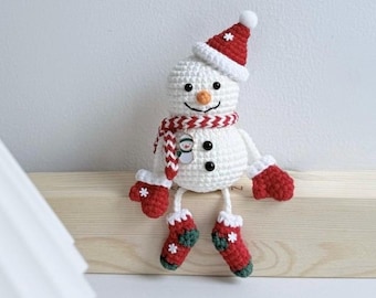 Può includere: Un pupazzo di neve all'uncinetto fatto a mano con cappello, sciarpa, guanti e stivali rossi. Il pupazzo di neve ha un naso a carota, occhi a bottone neri e una bocca sorridente. La sciarpa ha un piccolo ciondolo a forma di pupazzo di neve. Decorazione natalizia.