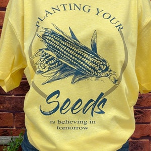May include: Yellow t-shirt with a blue graphic of corn and the text "Planting Your Seeds is believing in tomorrow."