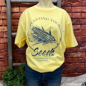 May include: Yellow t-shirt with a graphic of corn and the text "Planting Your Seeds is believing in tomorrow."