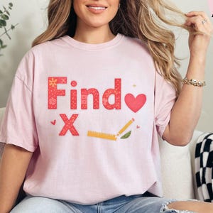 May include: A light pink t-shirt with the words "Find X" in red and floral patterns, a red heart, and a pencil and ruler graphic. The shirt is worn with blue jeans.
