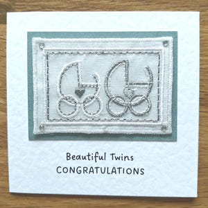 Carte faite main pour célébrer l'arrivée de bébés jumeaux, avec motif brodé.