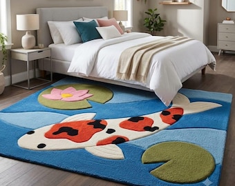 May include: A rectangular area rug featuring a large white, orange, and black koi fish swimming across a blue water-patterned background, accented with two green lily pads and a pink lotus flower with a yellow centre.