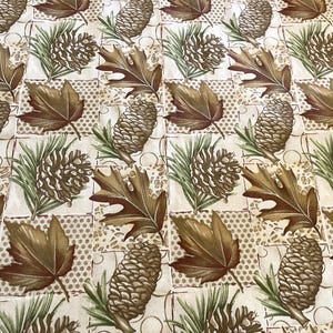 May include: A fabric with a repeating pattern of brown oak leaves, pine cones, and green pine needles on a cream-colored background. The design is arranged in a grid pattern with a dotted texture.