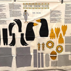 May include: A white fabric panel featuring cut-out patterns for a crow-themed project. The design includes crow heads, feet, wings, and sunflower accents. Text reads "AS THE CROW FLIES" and "MR. CROW".