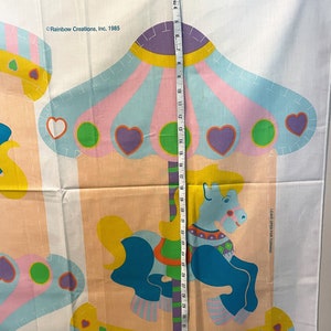 May include: A vintage fabric panel featuring a colorful carousel with a blue horse, pink, yellow, and green accents. The panel is marked "Rainbow Creations, Inc. 1985" and includes the text "Leave open for turning".