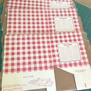 May include: Stack of red and white checkered pattern boxes. Each box has a label that says "PATTERNS" with space for size and style. The boxes are wrapped in clear plastic. The bottom box has instructions and the number "1" printed on it.