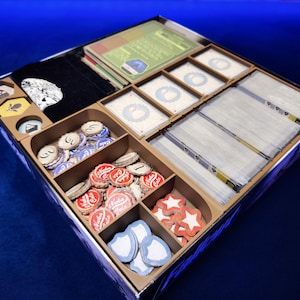 Könnte beinhalten: Ein hölzerner Spiel-Organizer, gefüllt mit verschiedenen Spielkomponenten. Enthält Karten, Spielsteine und einen schwarzen Beutel mit weißem Aufdruck. Der Organizer hat mehrere Fächer für eine effiziente Aufbewahrung.