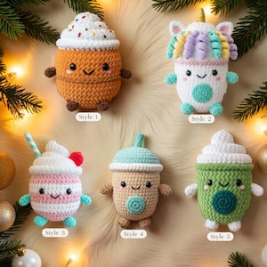 May include: A collection of five crocheted drink-themed ornaments. Styles include a coffee cup, unicorn, milkshake, boba tea, and a green drink. Each ornament has a smiling face and small arms and legs. The ornaments are in various colors.