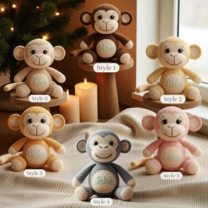 May include: A collection of six crocheted monkey plush toys in various colors, including brown, yellow, pink, and gray. Each monkey has a smiling face and is embroidered with a name. The monkeys are displayed on small wooden stands.