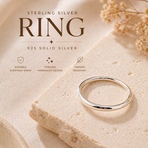 May include: A sterling silver ring, .925 solid silver, is displayed on a textured surface. The ring has a minimalist design and is durable for everyday wear. The image includes text that reads "RING".