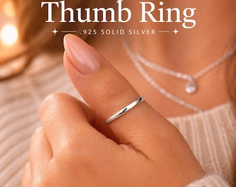 May include: A sterling silver thumb ring is displayed on a person's thumb. The ring is .925 solid silver and has a simple, polished design. The image also includes text that reads "Sterling Silver Thumb Ring .925 Solid Silver."