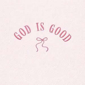 May include: A light pink background with the embroidered words "GOD IS GOOD" in a cursive font. A small pink bow is embroidered below the words. The image has a textured appearance.
