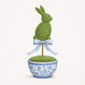 Può includere: Un coniglio topiary verde con un fiocco azzurro, posto in un vaso a motivi floreali blu e bianco. Il coniglio è fatto di materiale verde strutturato e il vaso ha un design dettagliato.