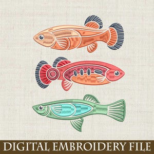 May include: Three embroidered fish in shades of orange, red, and green. Each fish has detailed stitching, with fins and tail in contrasting colors. The text "DIGITAL EMBROIDERY FILE" is at the bottom.