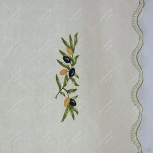 May include: Cream-colored fabric with an embroidered olive branch design. The branch features green leaves and black and yellow olives. A scalloped edge with green stitching borders the right side.