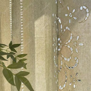 Può includere: Primo piano di una tenda verde oliva chiaro con un motivo floreale traforato. La tenda ha strisce verticali ed è parzialmente illuminata dalla luce solare, creando ombre. Una pianta verde fogliosa è visibile in primo piano.